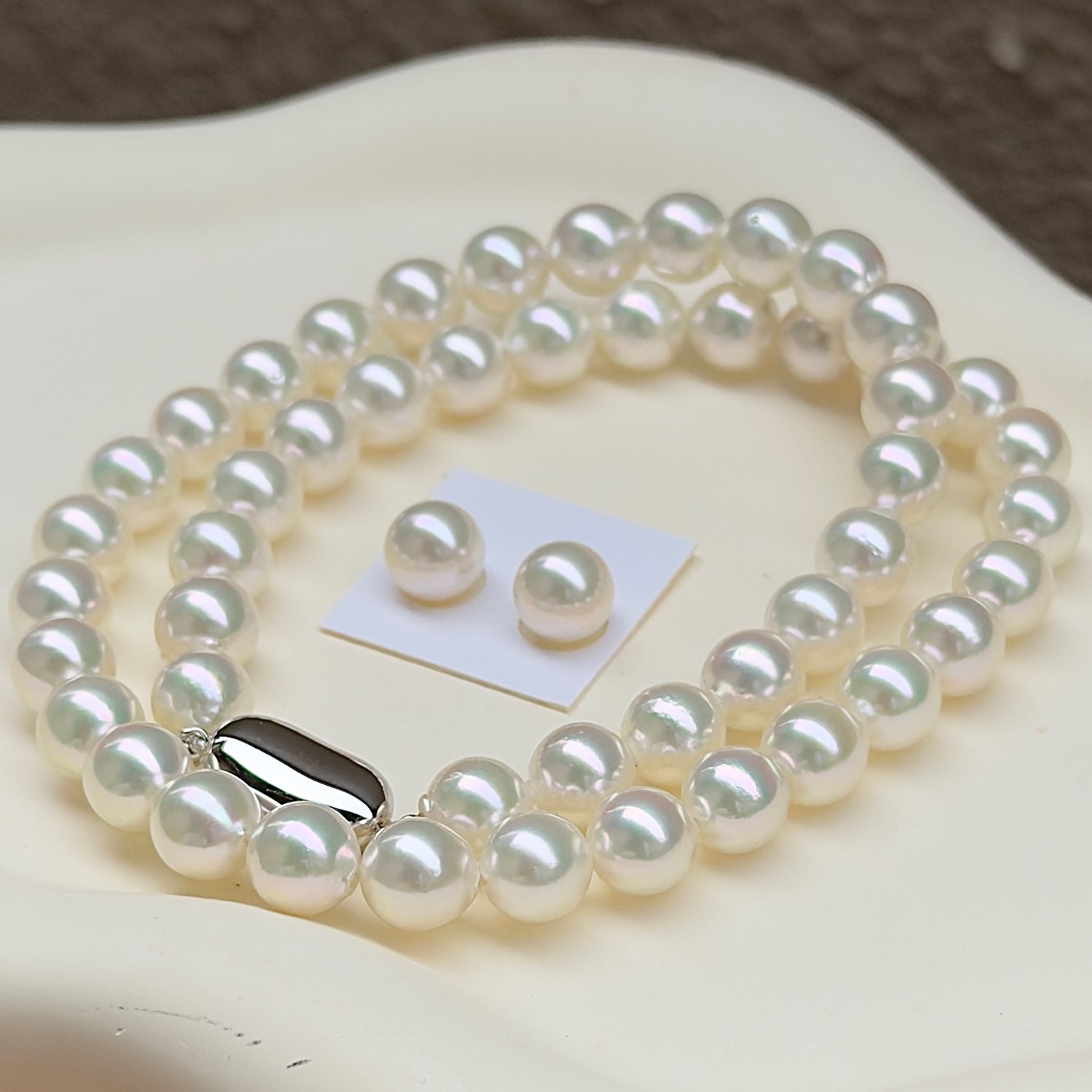 無調色アコヤ真珠ネックレス8.0-8.5㎜ホワイト系綺麗なグリーン干渉色モデル鑑別付き越物セットを斜め前から見ている