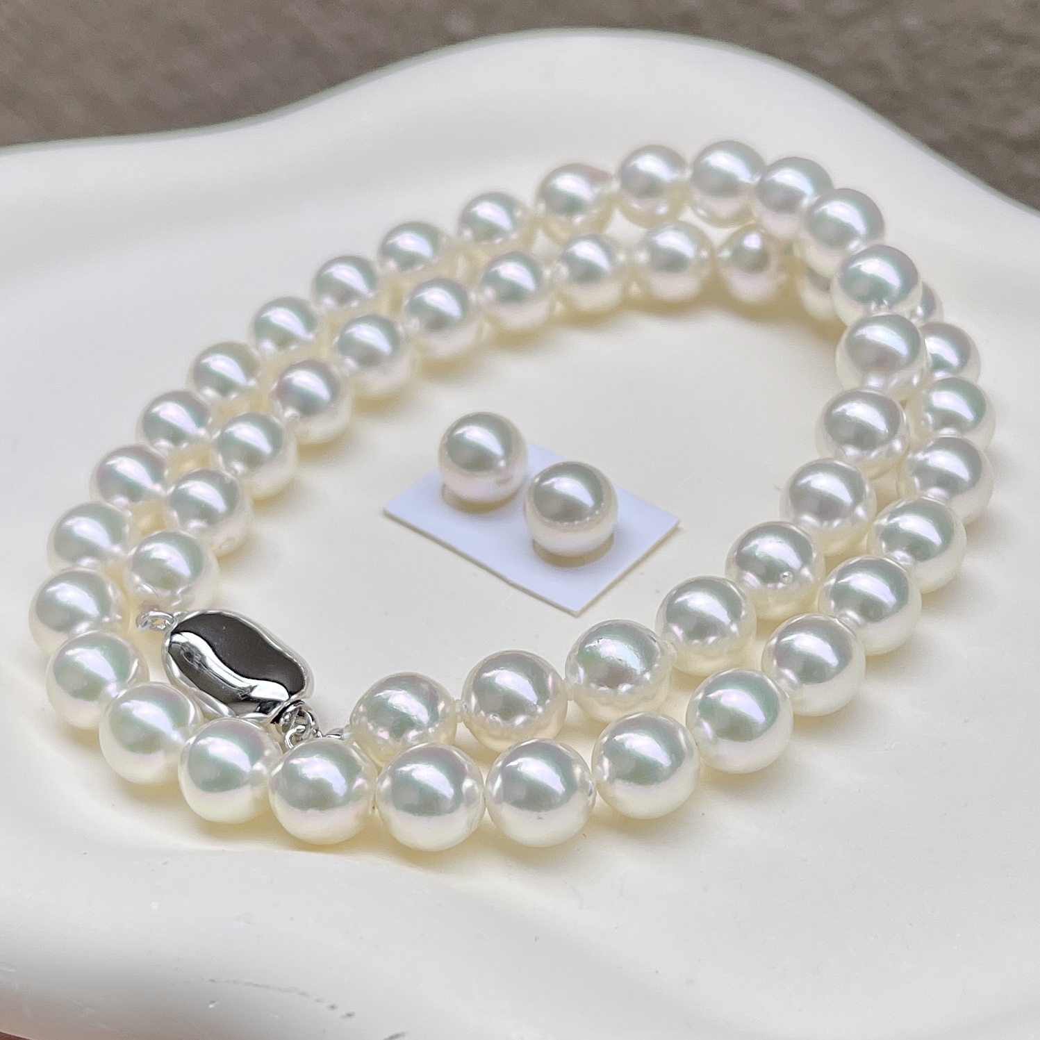 無調色アコヤ真珠ネックレス8.0-8.5㎜ホワイト系綺麗なグリーン干渉色モデル鑑別付き越物セットを斜め前から見ている